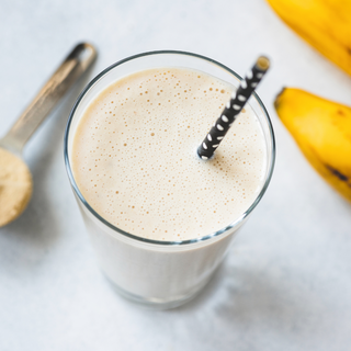 Cremiger Protein-Shake im Glas mit Strohhalm und Bananen – Zubereitungsbeispiel für Hanfproteinpulver