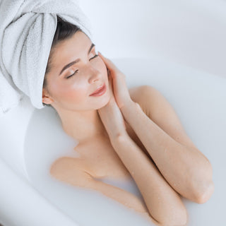 Frau entspannt im Basenbad mit Handtuch im Haar – regeneratives Wellness-Bad mit Dr. Wunder Basen Salzbad