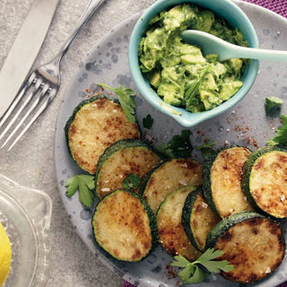 Gebratene Zucchinischeiben auf einem Teller mit Avocado-Dip, serviert mit Besteck