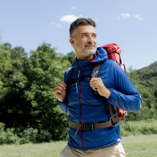 Wohlfühl-Porträt-Bild Magnesium 7Quell – Mann mittleren Alters beim Wandern mit rotem Rucksack in grüner Berglandschaft