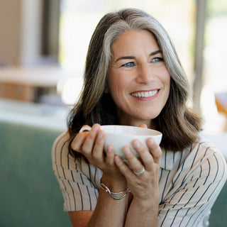 Lächelnde Frau hält weiße Teetasse in beiden Händen – Wohlfühl-Porträt-Bild für HEPY Tee